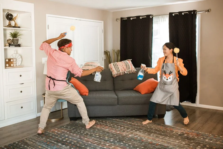 a-woman-in-a-green-shirt-and-black-gloves-vacuuming-a-gray-ottoman-5txz228u4eo